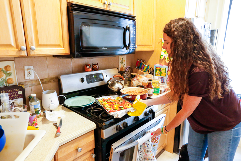 Jenna removing roasted vegetables from the oven.